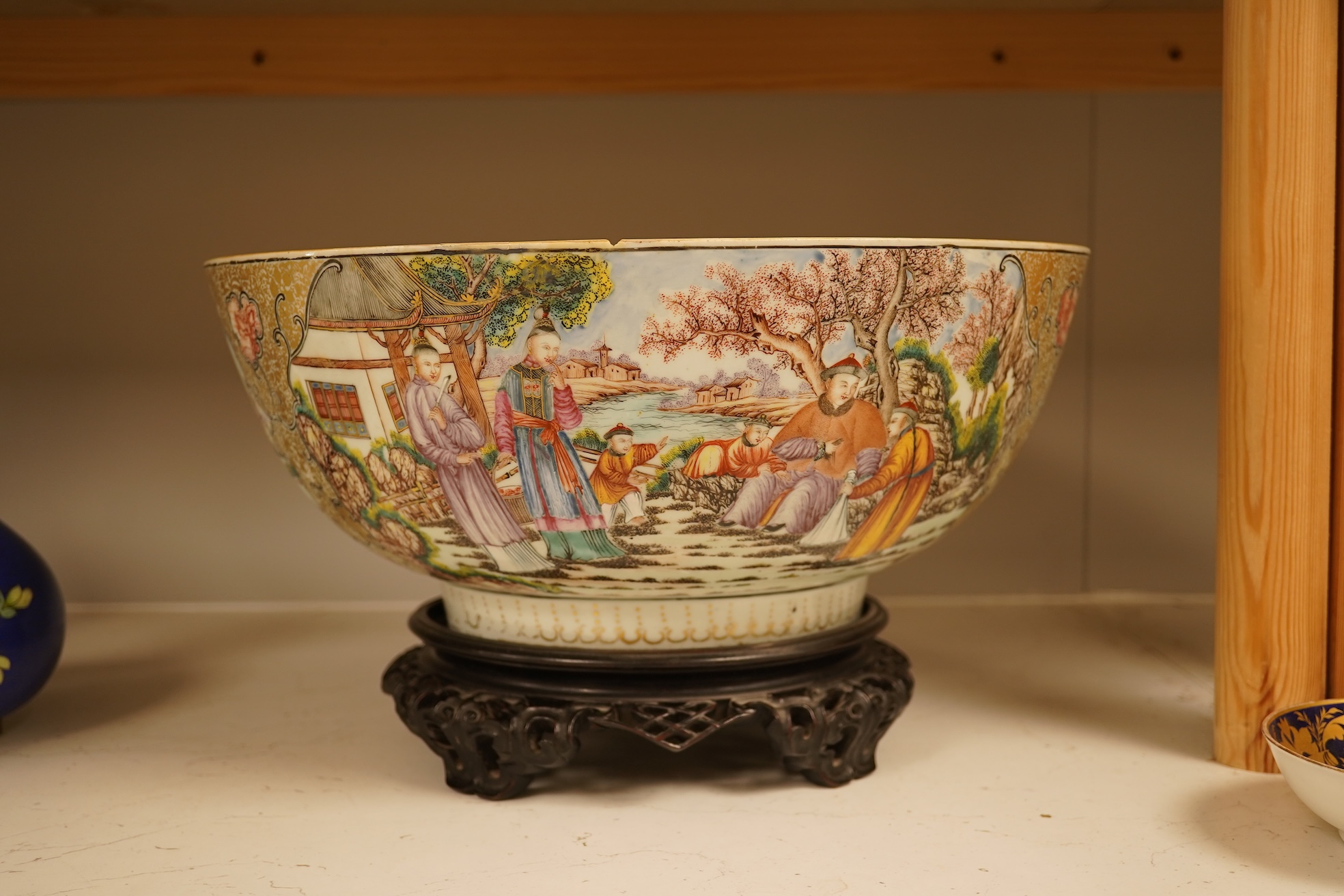 An 18th century Chinese famille rose figural bowl, on wooden stand, 34cm diameter.